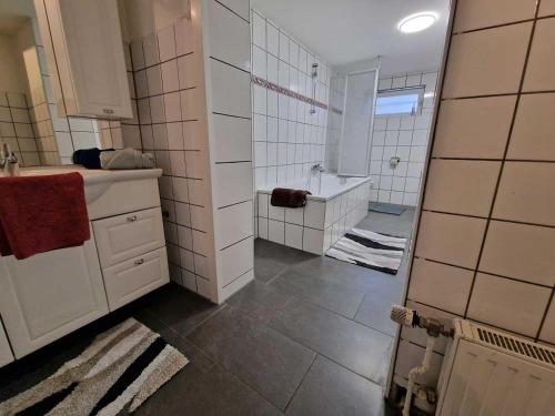 a white tiled bathroom with a tub and a sink at Ferienwohnung mit Smart-TV in Burscheid