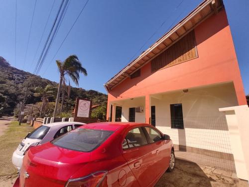 um carro vermelho estacionado em frente a um edifício em Pousada Areia Nova em Garopaba