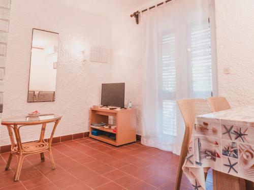 ein Wohnzimmer mit einem Tisch und einem TV in der Unterkunft Villa Gromaca in Omišalj