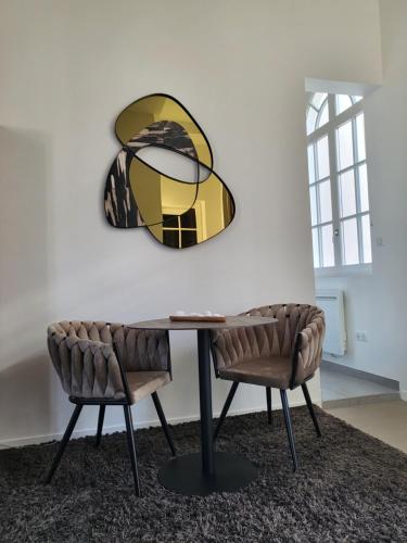 une table avec deux chaises et un miroir mural dans l'établissement Studio Terrasse, ancienne maison de champagne, à Reims