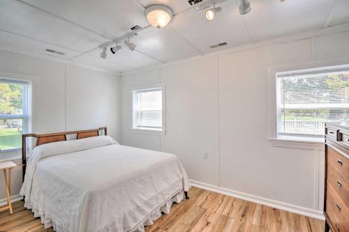a white bedroom with a bed and two windows at Romantic Waterfront Abode with Patio and Dock! in Deltaville