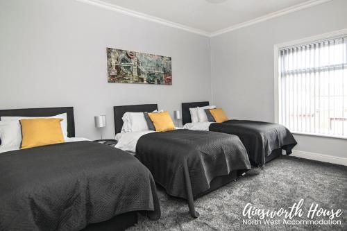 a bedroom with two beds with black and yellow pillows at Ainsworth House Serviced Accommodation in Bolton