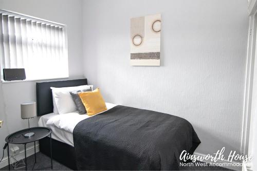 a bedroom with a bed with a yellow pillow on it at Ainsworth House Serviced Accommodation in Bolton