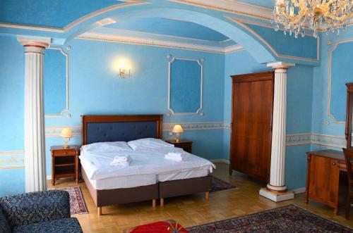 a bedroom with a bed with blue walls and a chandelier at Hotel Renesance Krasna Kralovna in Karlovy Vary