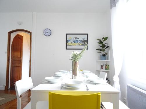 a white dining room with a white table and yellow chairs at Square-bnb - Duplex à 10min de Disneyland Paris in Montévrain