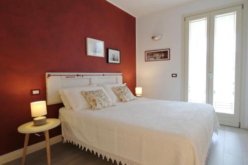 a bedroom with a white bed and a red wall at La Casa Di Cele in Desenzano del Garda