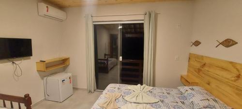 a bedroom with a bed and a television and a door at Pousada Gabriel in Praia de Araçatiba