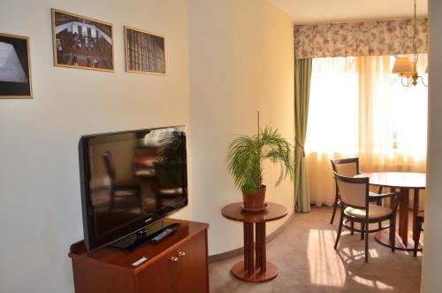 a living room with a flat screen tv and a table at Hotel Petr in Karlovy Vary