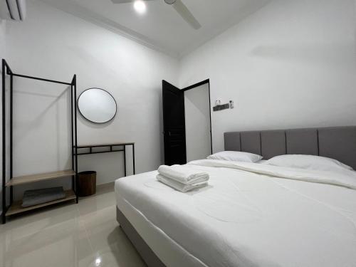 a white bedroom with a bed and a mirror at Laena Homestay in Kangar