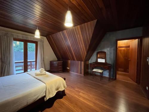 a bedroom with a large bed and a desk at Villa di Caserta by Capivari Lodge Home in Campos do Jordão