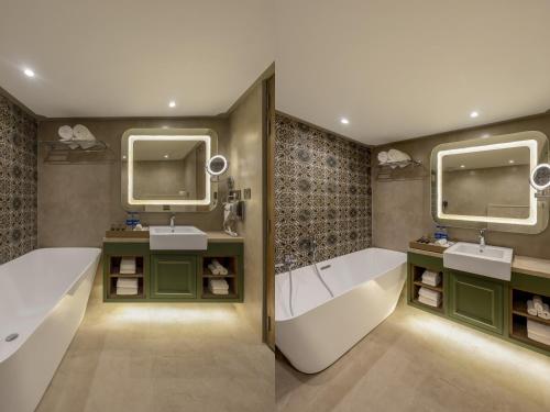 a bathroom with two sinks and a tub and two mirrors at Sarovar Portico Srinagar in Srinagar