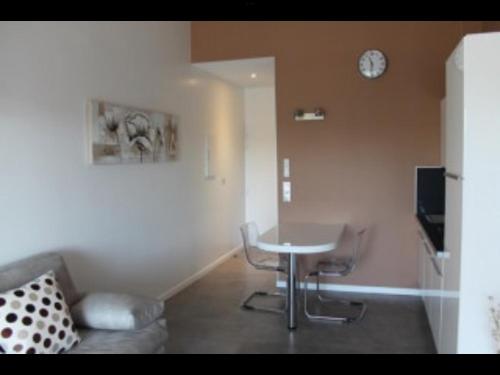 Zimmer mit einem Tisch und einer Uhr an der Wand in der Unterkunft Coquet studio classé trois étoiles in Balaruc-les-Bains