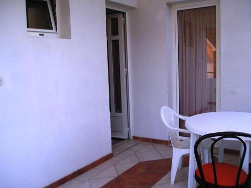 een witte tafel en stoelen in een kamer met een witte muur bij Apartments Jele II in Sveti Petar