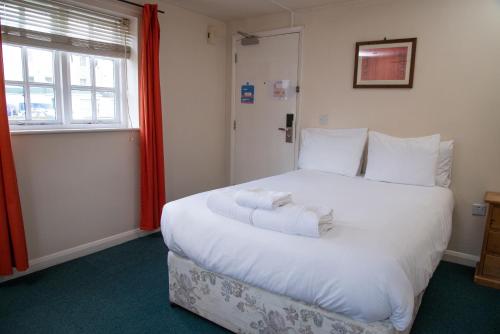 a large white bed in a room with a window at Royal Hotel, Bar & Grill in Purfleet