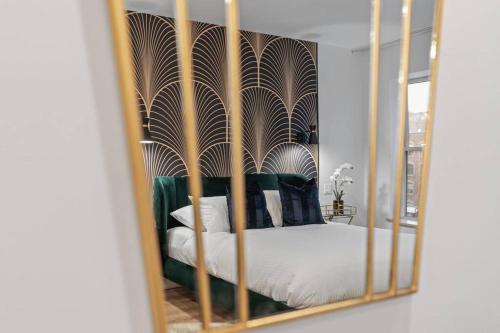 einen Spiegel, der ein Schlafzimmer mit einem Bett mit weißer Bettwäsche reflektiert in der Unterkunft Initial / Art-déco / Quebec in Québec