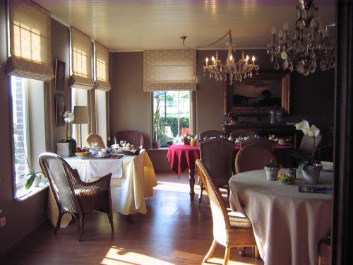 a dining room with tables and chairs and a chandelier at B&B Het Welthof in Bree