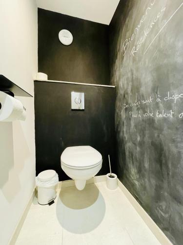 a bathroom with a white toilet and a black wall at Residence Louis Quartier Casino in Vittel