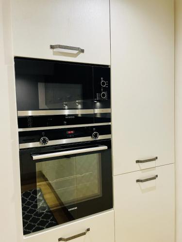 a black microwave oven in a white kitchen at Residence Louis Quartier Casino in Vittel