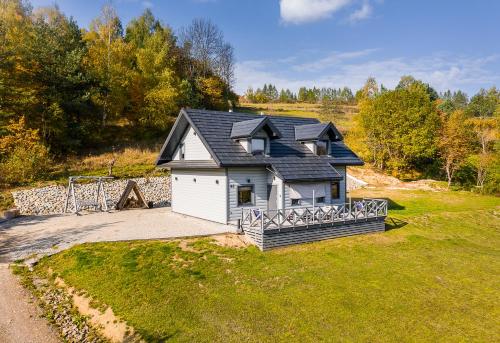 a small white house with a black roof at Antkowe Wzgórze in Polańczyk
