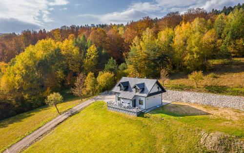 a small white house on a grassy field with trees at Antkowe Wzgórze in Polańczyk