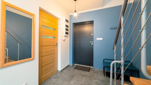 een hal met een zwarte deur en blauwe muren bij Apartamenty EverySky - Dom Reymonta 9 in Karpacz