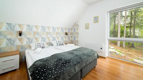 een slaapkamer met een bed en een groot raam bij Apartamenty EverySky - Dom Reymonta 9 in Karpacz
