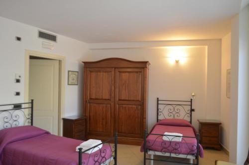 a bedroom with two beds and a wooden cabinet at Casa per ferie religiosa Figlie di Nazareth in Pisa