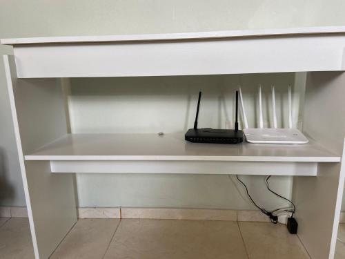 a white desk with a laptop and a phone on it at Aluga-se casa para Temporada in Águas de Lindóia