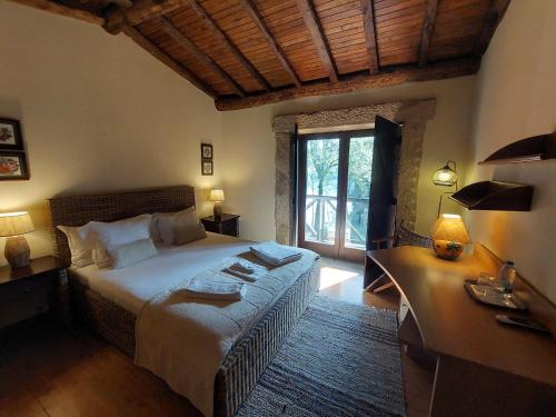 a bedroom with a large bed and a large window at Quinta do Caneiro in Geres