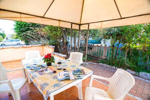 a table with white chairs and an umbrella at residence lu soli budoni affitti in Budoni