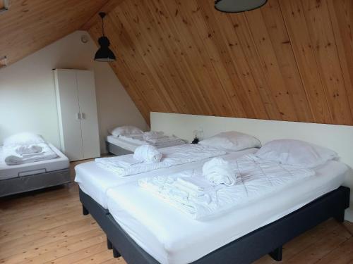 two beds in a room with wooden ceilings at Ruim appartement in prachtige fiets-wandelomgeving in Abcoude