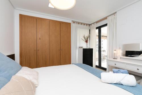 a bedroom with a large white bed and a television at Veramar Beach Apartment in Valencia