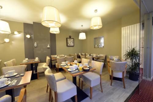 une salle à manger avec tables, chaises et lustres dans l'établissement France Hôtel, à Niort