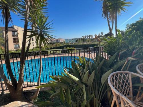 une piscine avec des palmiers et une clôture dans l'établissement T2 Rez de jardin 4 personnes acces direct piscine superbe vue mer / Parking privé ombragé l'AM, à Six-Fours-les-Plages