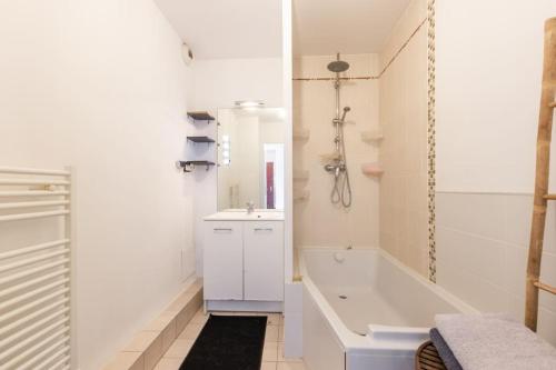 een witte badkamer met een bad en een wastafel bij Disney 18'Km - Appart Terrasse - 8'min Gare in Meaux