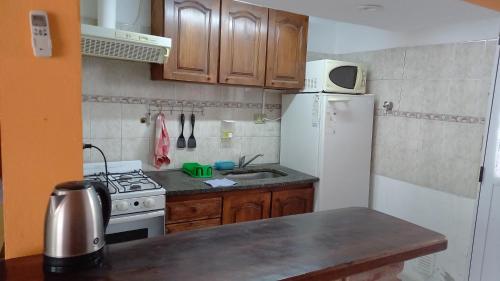 - une cuisine avec des placards en bois et un réfrigérateur blanc dans l'établissement Rinconada 2, à Las Grutas