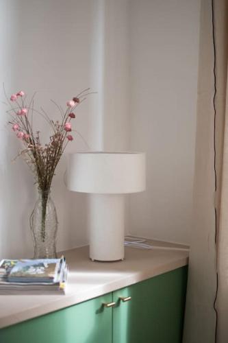 une table avec une lampe et un vase avec des fleurs. dans l'établissement Brune, Clim - Ultra Central, à Arles