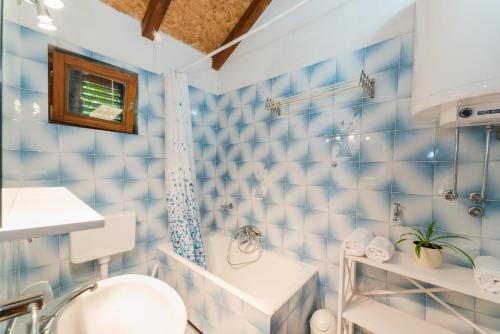 a blue tiled bathroom with a toilet and a sink at Apartmani Bugenvilija in Brbinj