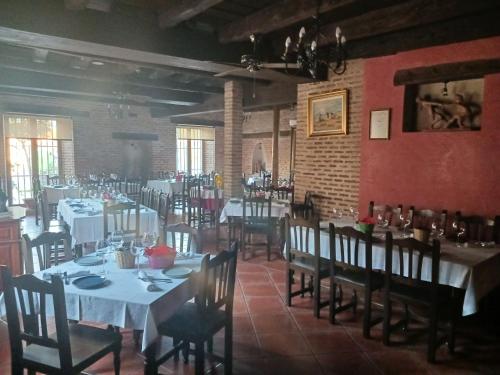 um restaurante com mesas e cadeiras brancas e uma parede de tijolos em Hotel Restaurante Doña Elvira em Nava del Rey