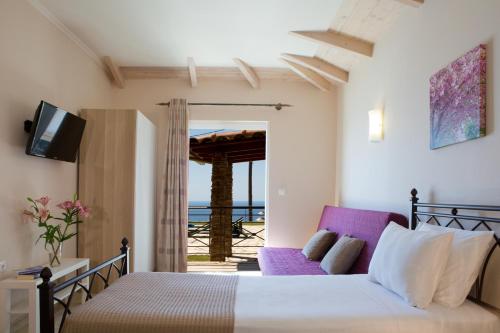 a bedroom with a bed and a tv and a couch at PANTHEON RESORT AND VILLAS in Agios Nikitas