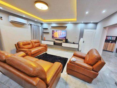 uma sala de estar com mobiliário de couro e uma televisão de ecrã plano em Tlokweng Rose Garden Guesthouse em Gaborone