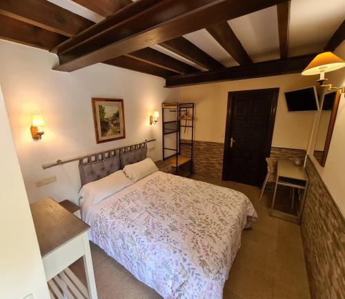 1 dormitorio con cama, mesa y TV en Amaicha casona en Ribadesella