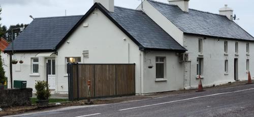 a white house with a black roof on a street at Peacock Farm Estate Self Contained Lodges in Cork