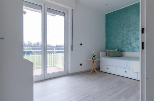 een witte kamer met een bed en een groot raam bij Casa Martina in Castelletto sopra Ticino