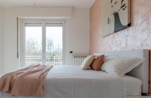 - une chambre blanche avec un grand lit et une fenêtre dans l'établissement Casa Martina, à Castelletto sopra Ticino