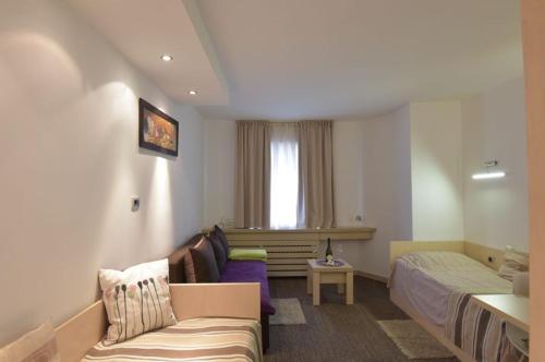 Habitación de hotel con sofá y cama en Konaci Kopaonik Lux Apartmani en Kopaonik