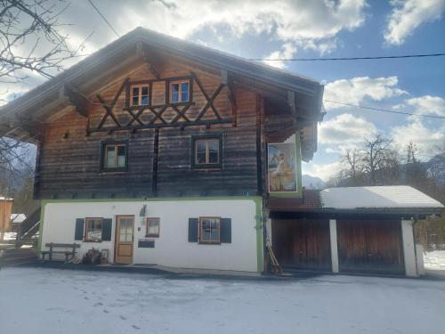 a wooden house with snow in front of it at Panoramaferienwohnung Resch in Bischofswiesen