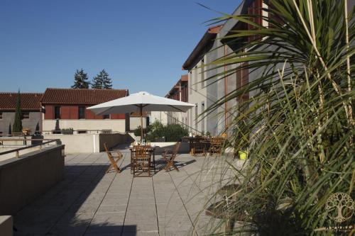 une terrasse avec une table, un parasol et des chaises dans l'établissement Adonis Carcassonne, à Carcassonne