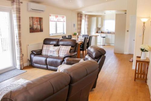 a living room with a leather couch and a table at Fabulous detached lodge with hot tub two nights minimum stay in Bridgnorth