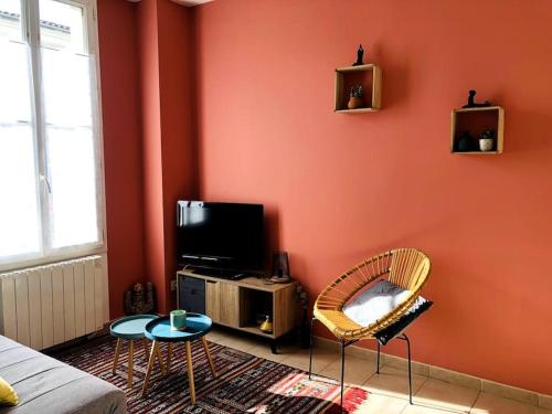 a living room with orange walls and a tv and chairs at Joli T2 en centre-ville de Rochefort in Rochefort
